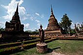 Thailand, Old Sukhothai - Wat Sa Si. Secondary chedi and main chedi with in front the Sukhothai style statue of  walking Buddha in the vitarka mudra.  